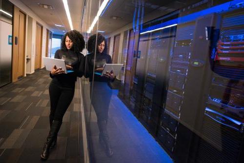 A data scientist stands outside a network systems room.